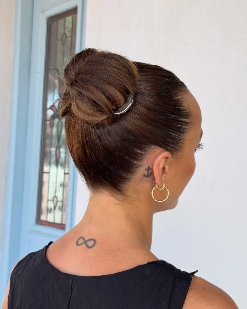 Sleek high brunette bun finished with a gold hair clip, by Circles of Hair Perth